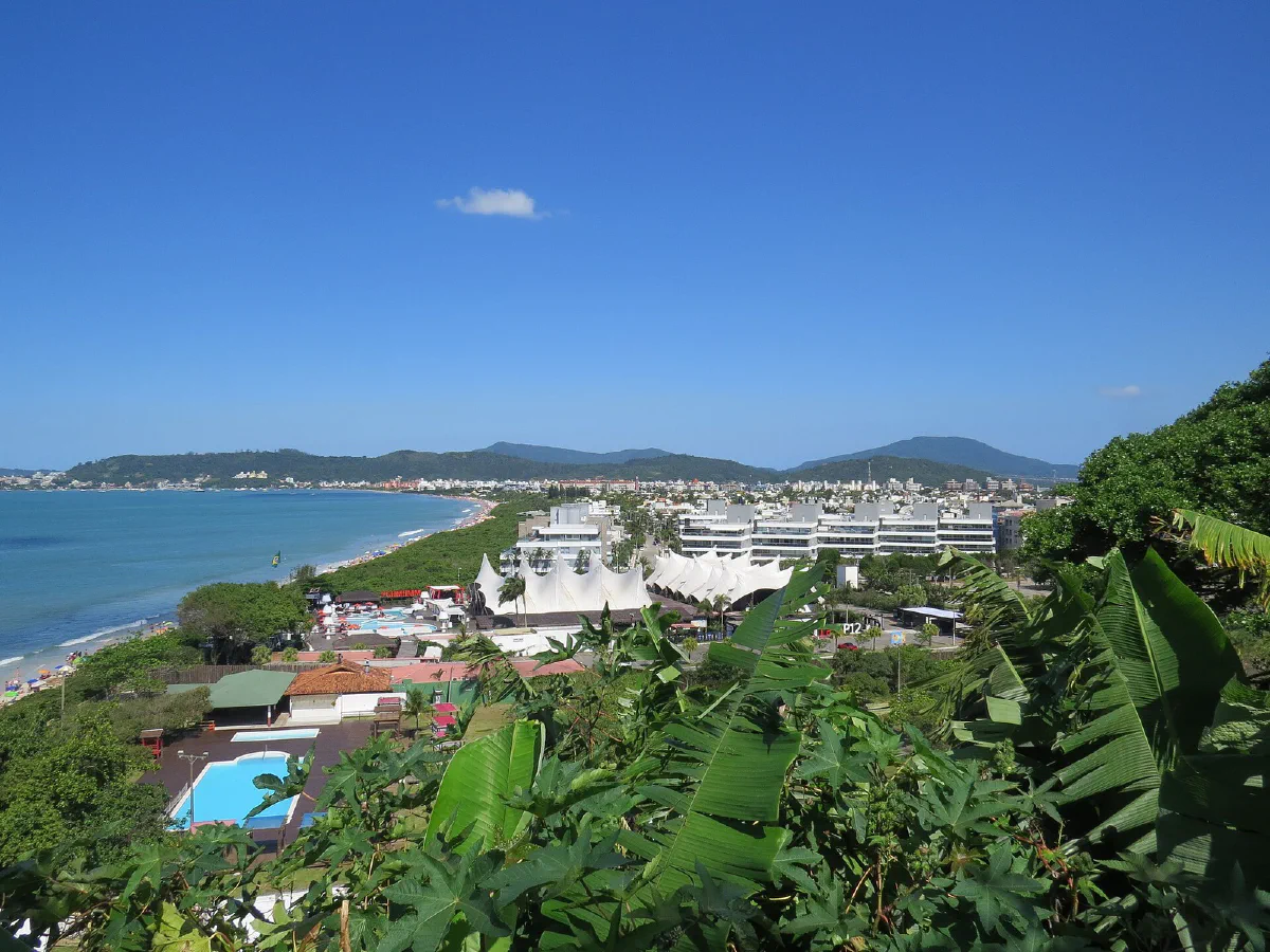 Praia e bairro de Jurerê Internacional vistos do alto, com o mar à esquerda e construções junto à orla.