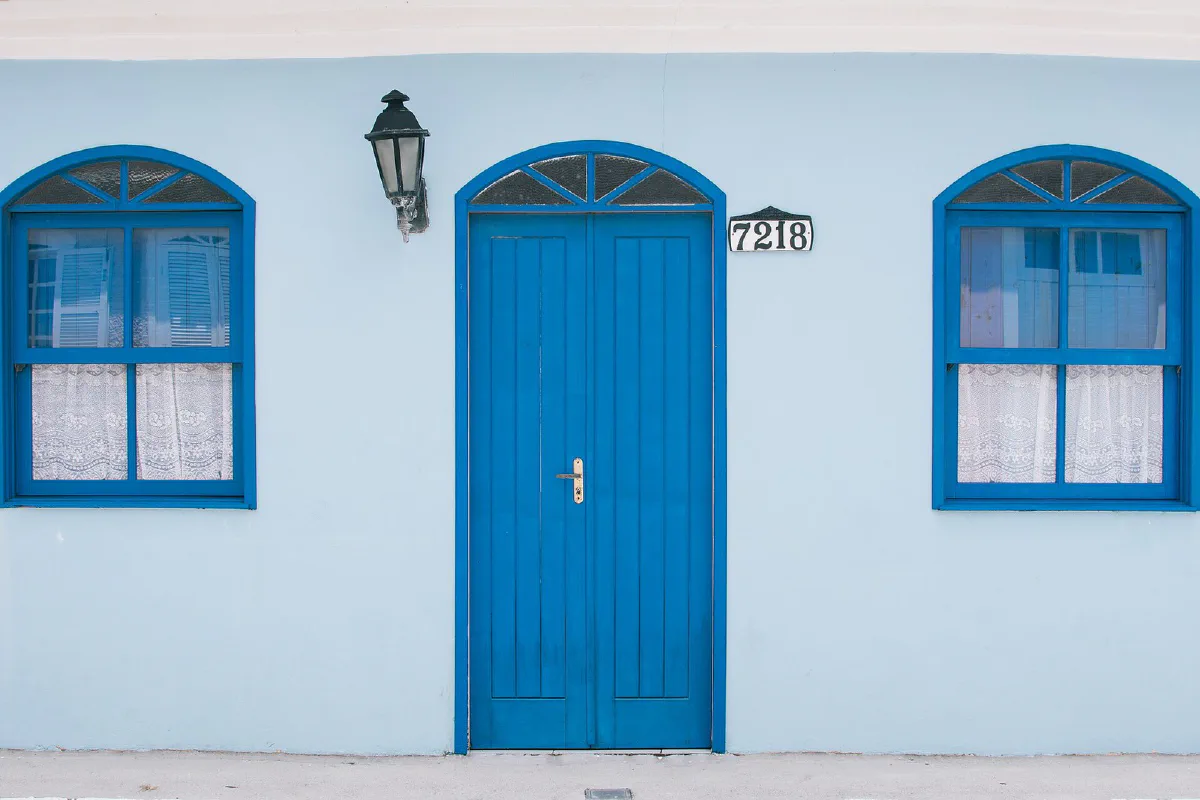 Fachada de uma casa no Ribeirão da Ilha, com porta e janelas azuis.