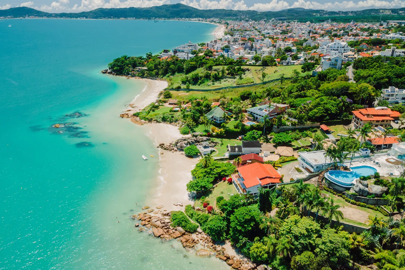 Vista aérea panorâmica de uma praia de água turquesa e areia clara em Florianópolis (SC)
