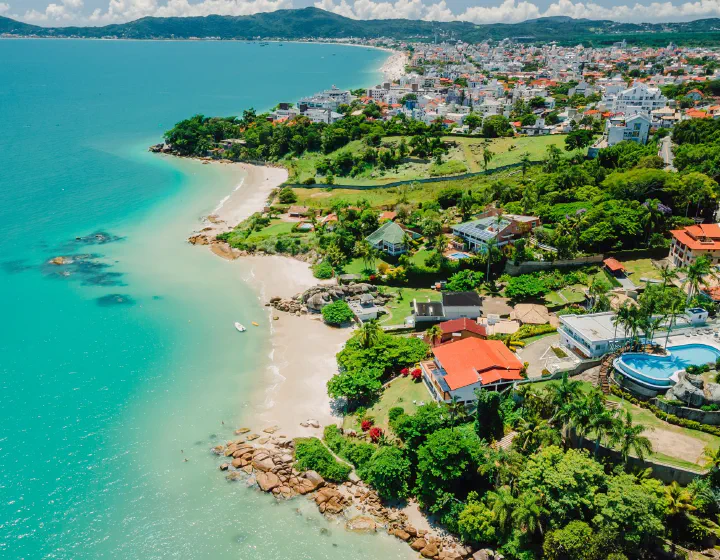 Vista aérea panorâmica de uma praia de água turquesa e areia clara em Florianópolis (SC)