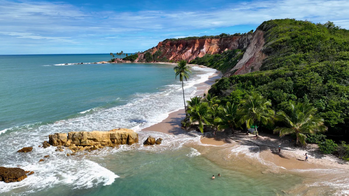 Falésias vermelhas, pedras e coqueiros na Praia de Coqueirinho, em Conde (PB)