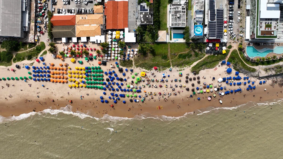 Vista aérea de guarda-sóis coloridos e barracas na areia de uma praia de João Pessoa (PB)
