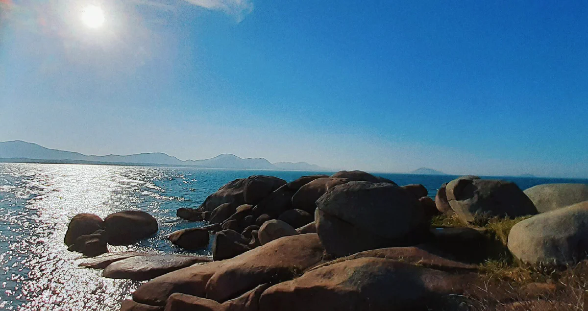 Pedras grandes à beira da água na trilha da Barra da Lagoa.