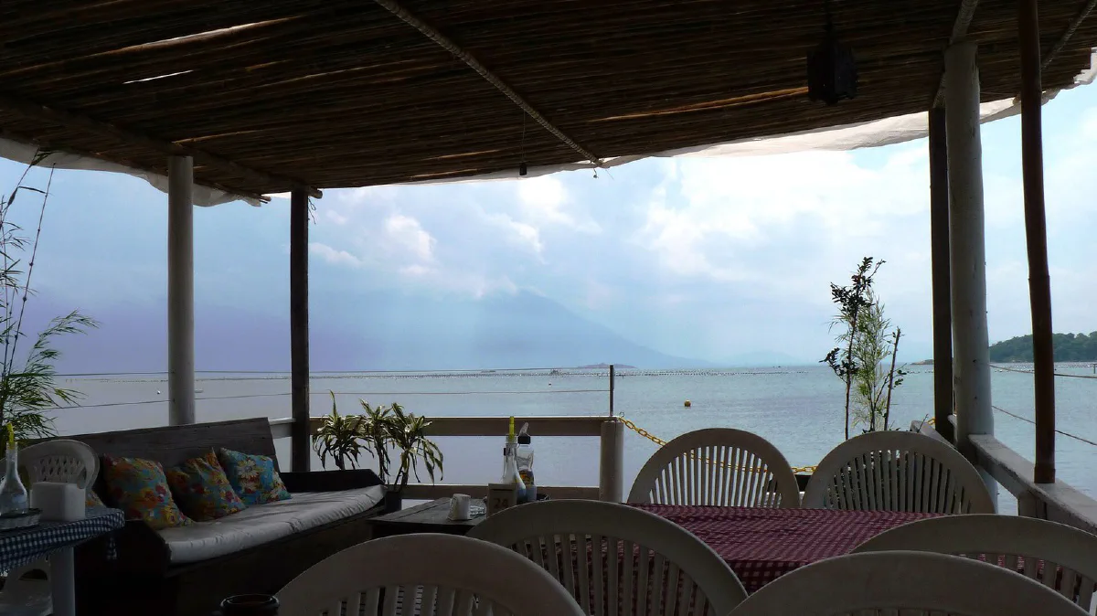 Terraza cubierta de un restaurante de mariscos, con mesas y vista a la bahía de Ribeirão da Ilha.
