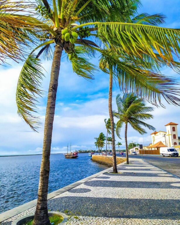 Calçada da Passarela do Álcool com coqueiros e um mar azul marinho abaixo em Passarela do Álcool em Porto Seguro na Bahia