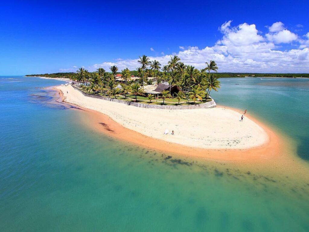 ilha com a água em tons de verde e azul o Arraial d’Ajuda Eco Resort no meio no Apaga-Fogo